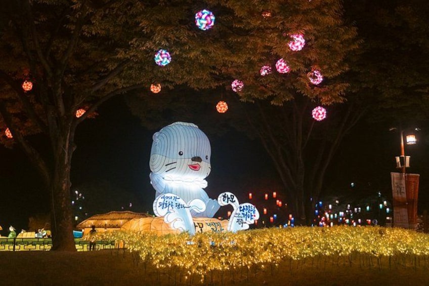 A large illuminated sculpture of a bear in a park at night. 2