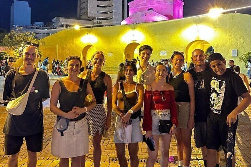 Un groupe de personnes posant devant un mur jaune vif, illuminé, et orné d’arches. 2