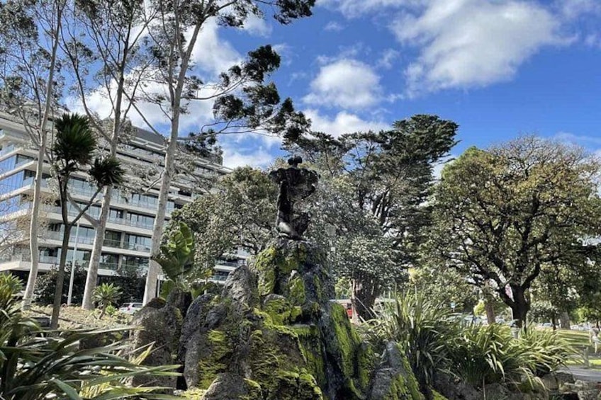 Un parc avec une statue, des arbres et un bâtiment en arrière-plan. 4