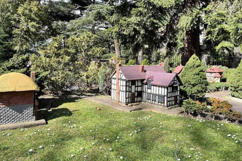 Une maison traditionnelle à colombages, avec un toit rouge, entourée d’une végétation luxuriante et d’arbres. 5