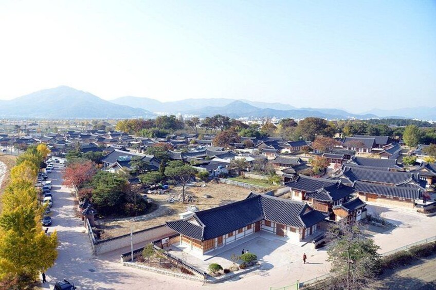 A traditional Korean village with wooden houses, a clear sky, and mountains in the background. 3