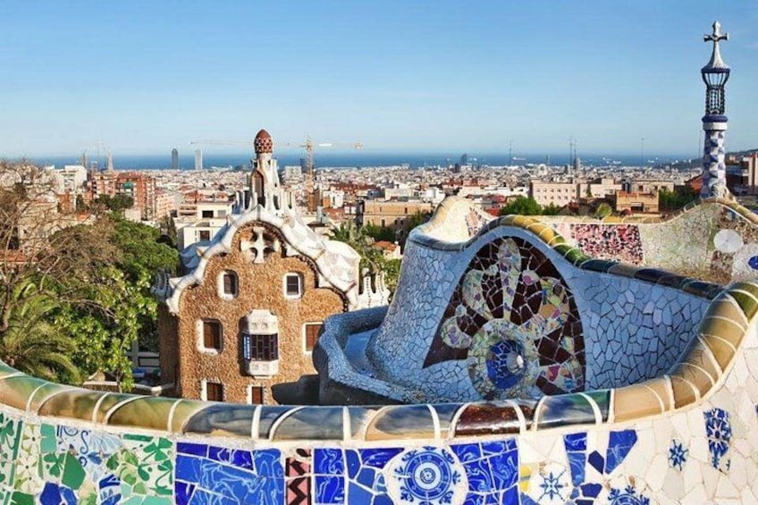 A view of Park Guell in Barcelona, featuring the Casa Batlló and Casa Milà with mosaic tile work. 3