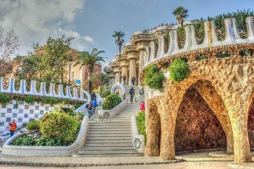 A stone bridge with arches, a checkered pattern wall, and a staircase leading up to a building. 1