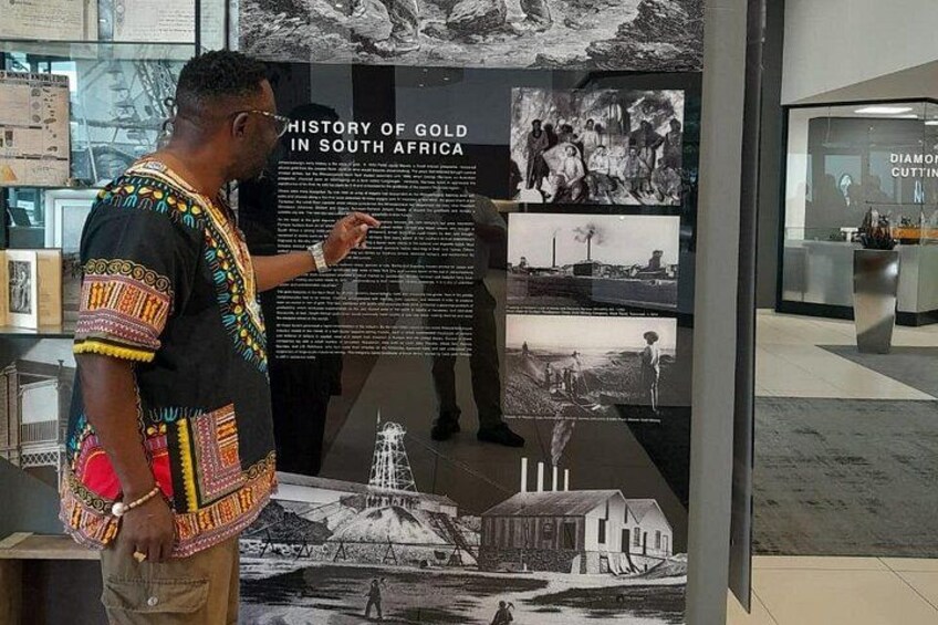A man standing in front of a historical display about gold in South Africa. 3
