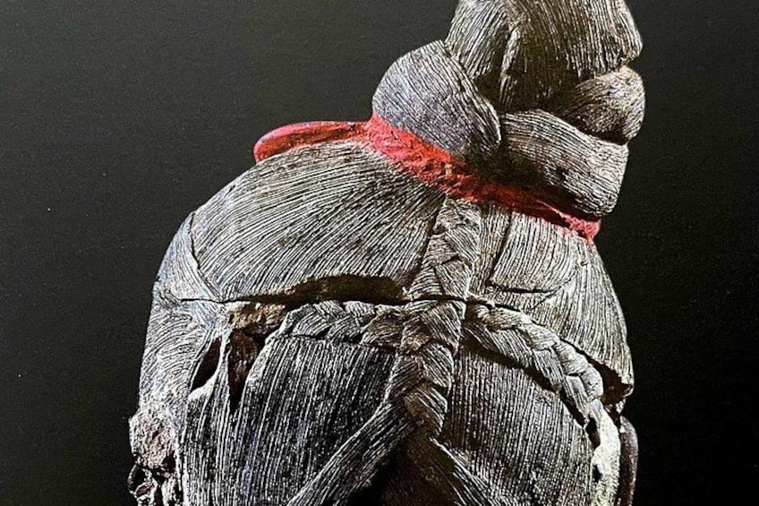 Una escultura con superficie texturizada y un lazo rojo. 2