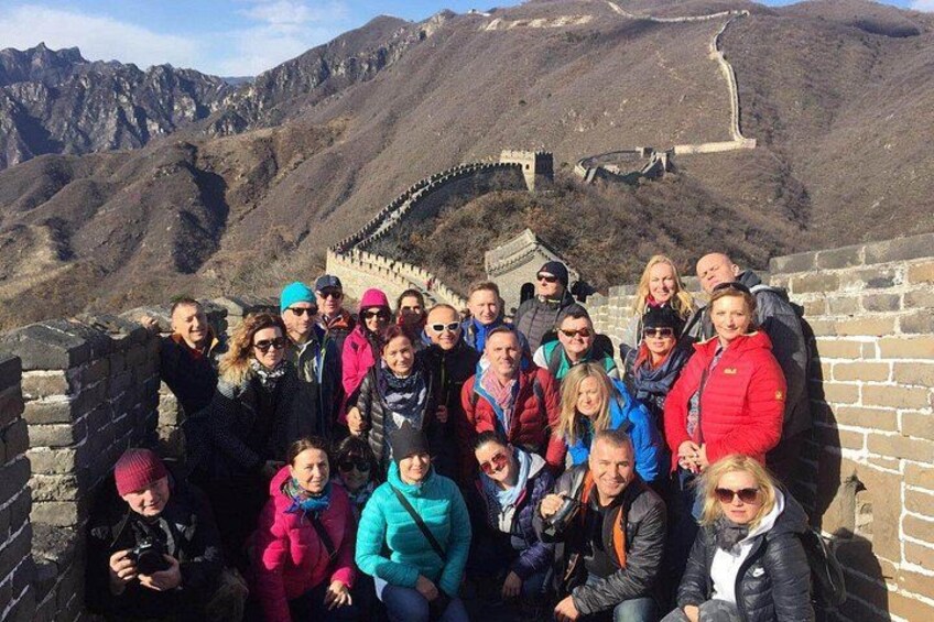 A group of people standing on the Great Wall of China with mountains in the background. 2