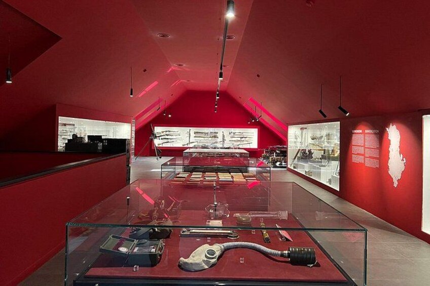 En udstilling på et museum med røde vægge, glasmontre og informationsskilte. 5