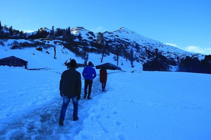 A group of people walking on a snowy path with mountains in the background. 2
