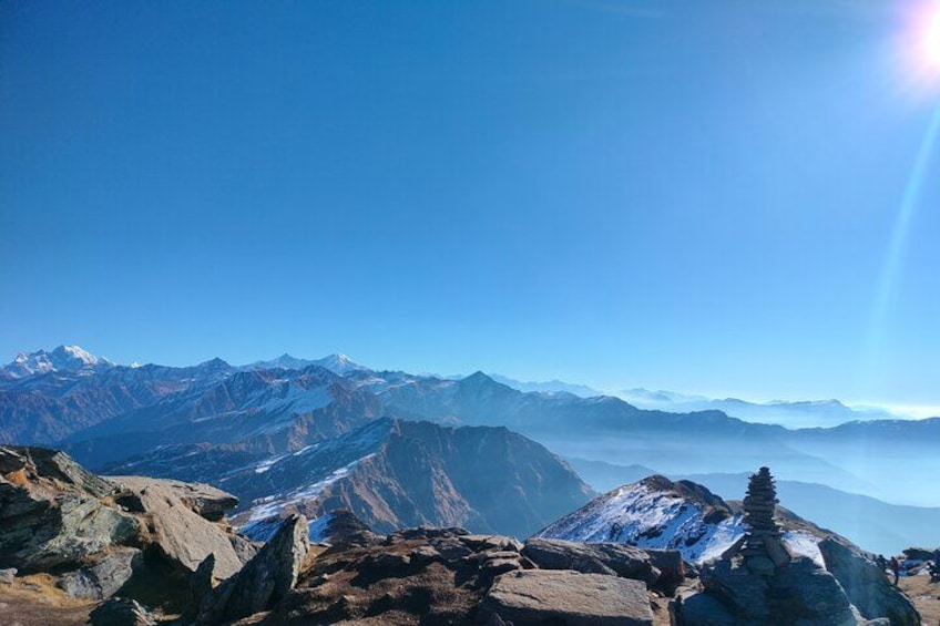 A mountain range with snow-capped peaks, rocky terrain, and a clear blue sky. 4