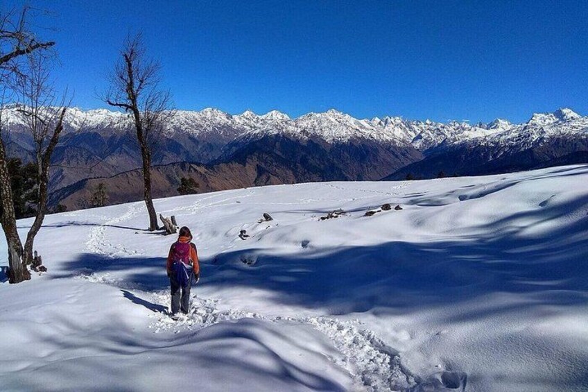 A person hiking in a snowy landscape with mountains in the background. 1
