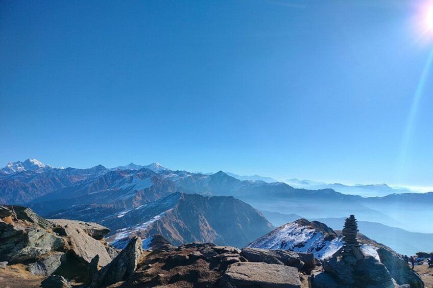 A mountain range with snow-capped peaks, rocky terrain, and a clear blue sky. 4