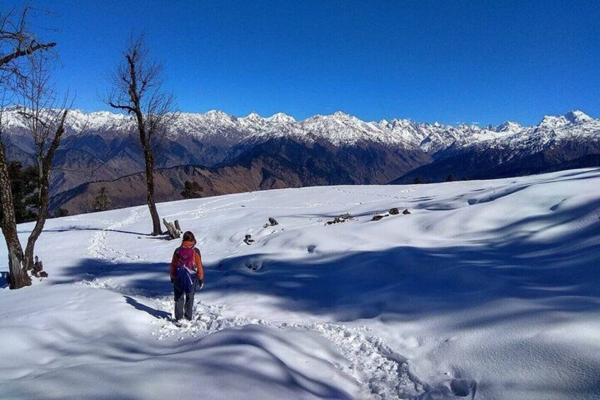 A person hiking on a snow-covered trail with mountains in the background. 1