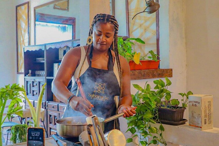 Una persona cucina in una cucina con piante e un orologio in vista. 1