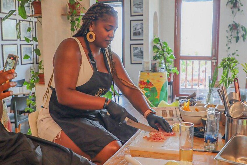 Una persona prepara cibo a tavola, con diversi utensili da cucina e ingredienti. 5