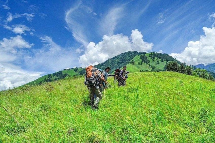 Two hikers on a grassy hill with a clear sky. 5