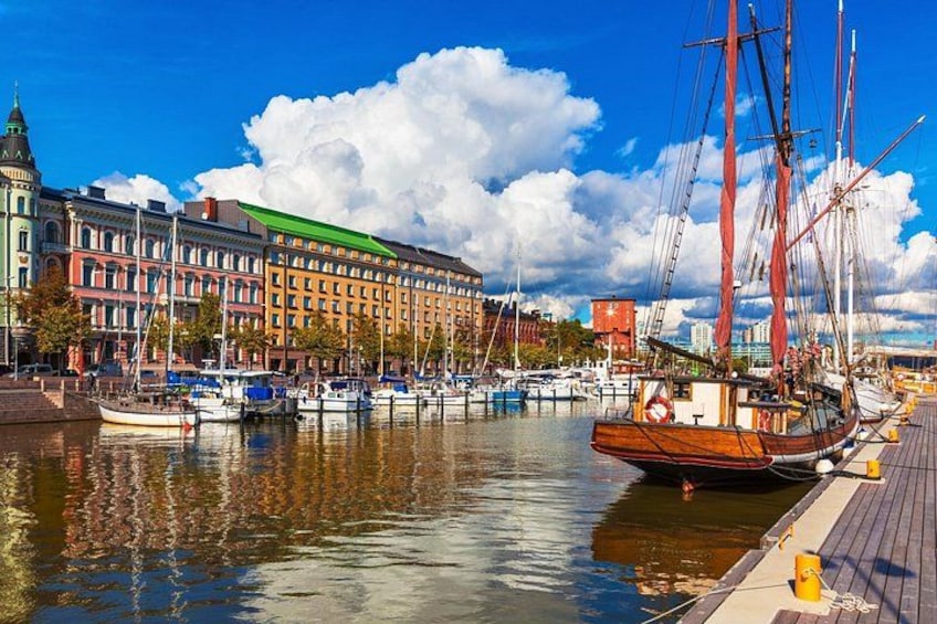 Un puerto con un gran barco de vela de madera, edificios coloridos y un cielo azul despejado. 1
