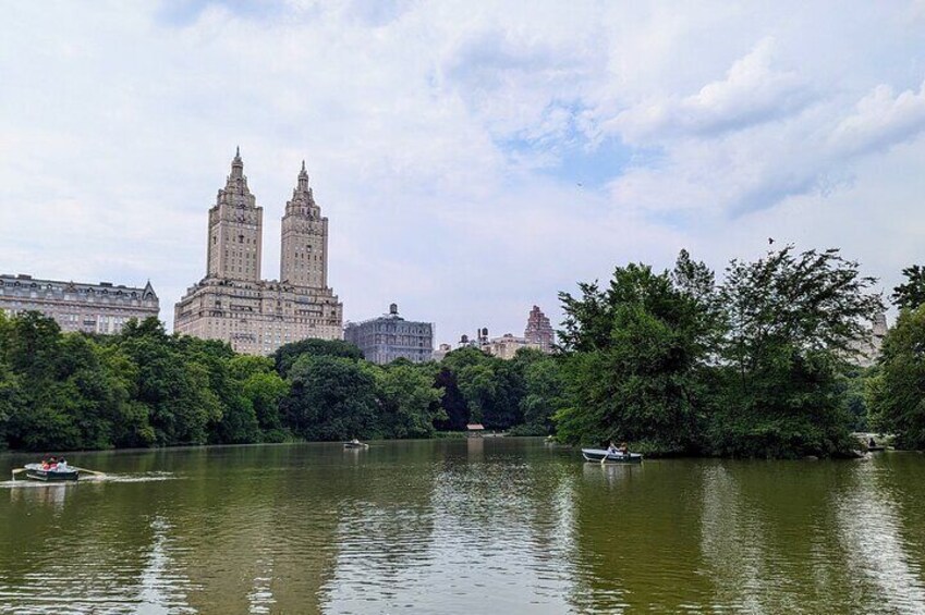 A river with boats, a large building with two towers, and trees along the banks. 1