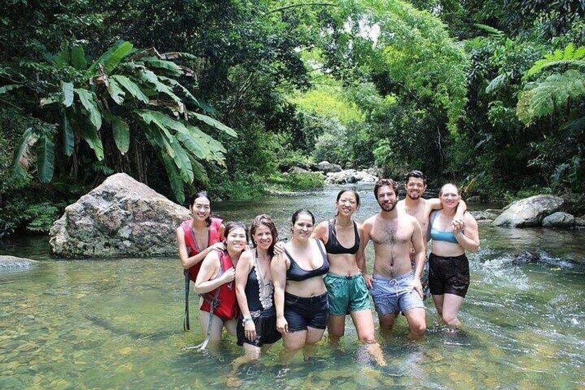 A group of people standing in a clear stream surrounded by lush greenery. 3
