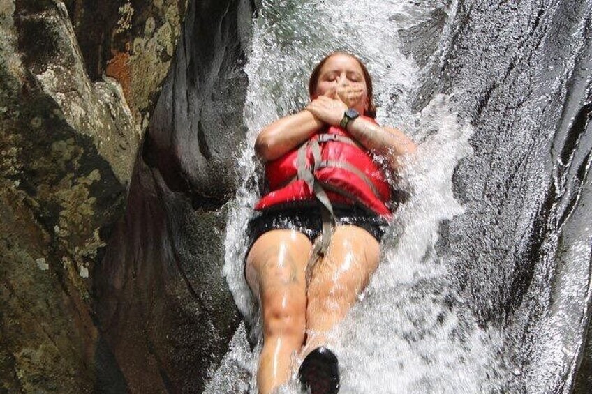 Una persona con chaleco salvavidas rojo se desliza por una cascada. 2