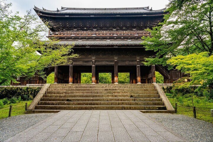 A traditional Japanese building with a tiled roof, wooden columns, and a stone staircase leading up to it. 3