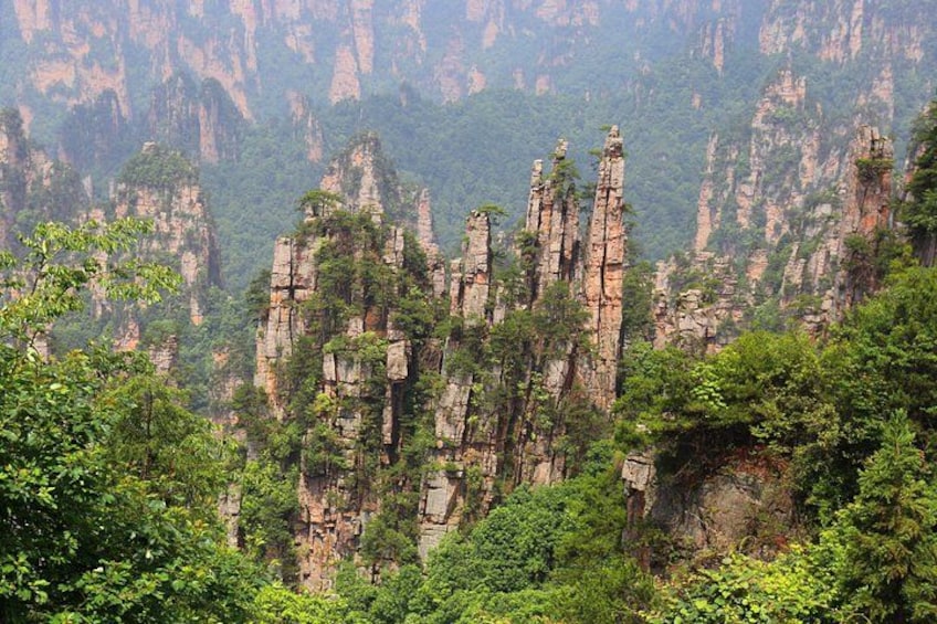 A mountainous landscape with tall, narrow rock formations and dense green foliage. 1