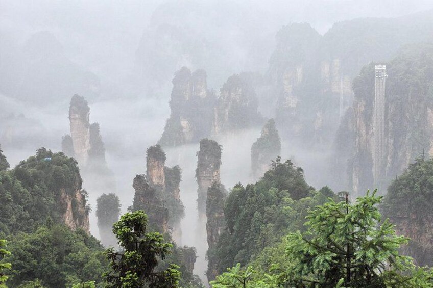 A misty landscape with towering rock formations and dense greenery. 5