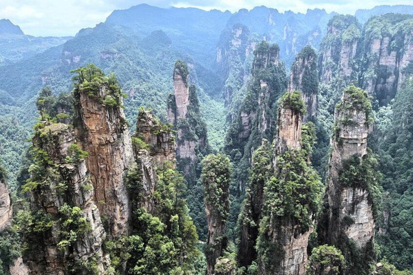 A landscape of towering limestone peaks with dense forest vegetation. 2