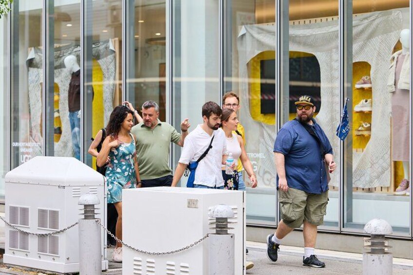 People walking outside a store with mannequins and a large glass window. 5
