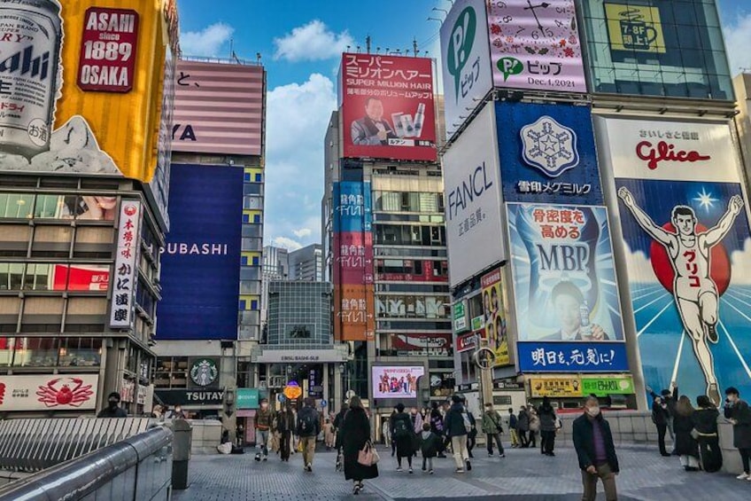 Une rue animée en milieu urbain, avec de nombreux panneaux publicitaires et enseignes commerciales rédigés dans une langue étrangère. 2