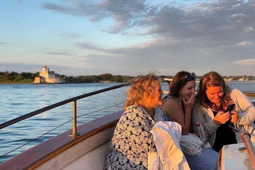 Three people sitting on a boat with a body of water and a distant building in the background. 3