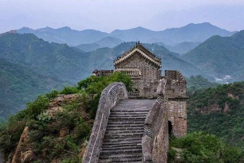 Un escalier en pierre mène à un bâtiment traditionnel chinois, doté d’un toit en tuiles, et qui est entouré de montagnes verdoyantes. 2