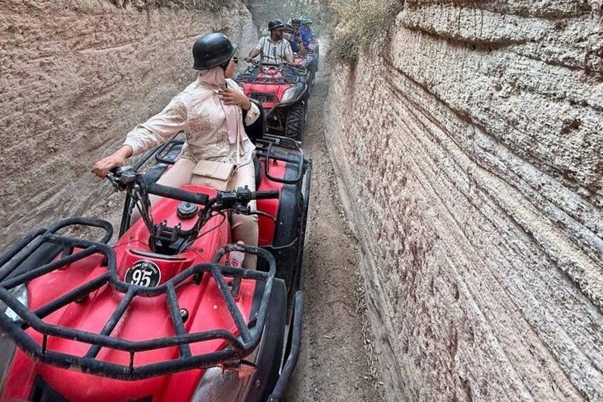 Un grupo de personas manejando vehículos todo terreno rojos a través de un cañón estrecho y rocoso. 3
