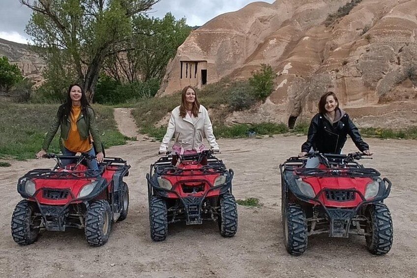 Tres personas en cuatrimotos en un terreno rocoso al aire libre, con un sendero de tierra y vegetación escasa. 1