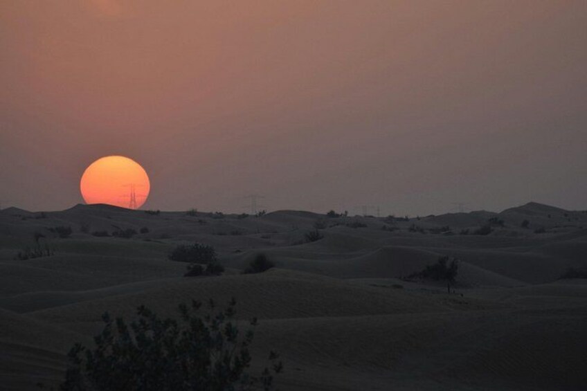 A desert landscape with rolling sand dunes and a setting sun. 5