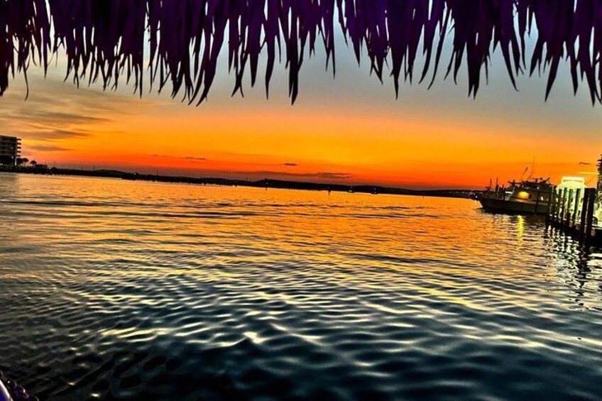 A sunset over a calm body of water with reflections of the sky, a dock, and a building in the background. 5