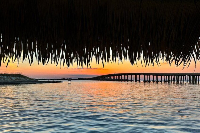 A sunset over water with a pier extending into the distance. 2