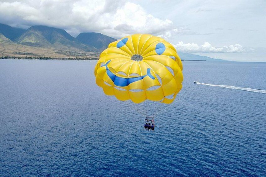 Une personne pratiquant le parachute ascensionnel au-dessus d’une étendue d’eau, avec des montagnes en arrière-plan. 2