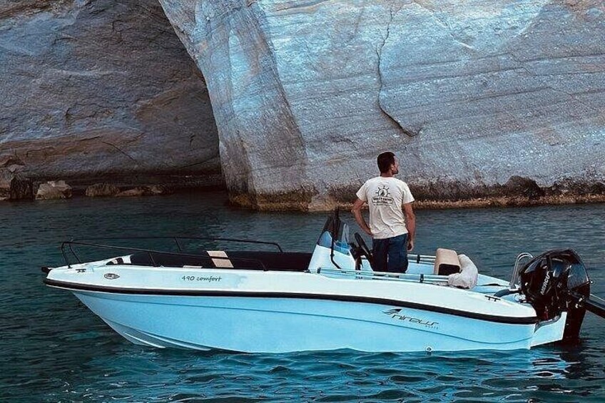 A boat named 'Comfort' with a person standing at the back, near a large rock formation. 1