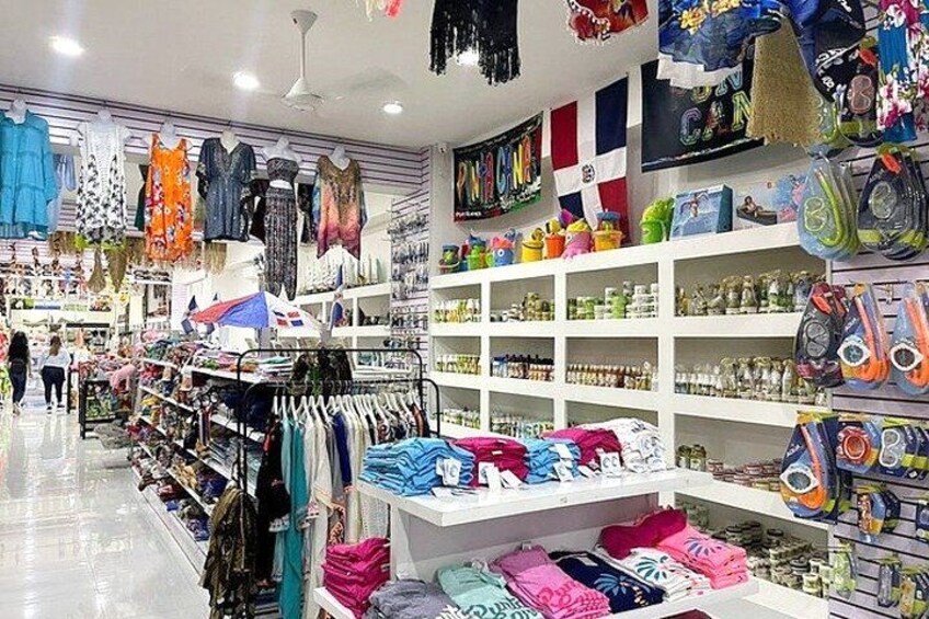 Una tienda de ropa con perchas llenas de prendas, estantes de accesorios y una gran variedad de artículos coloridos a la vista. 1