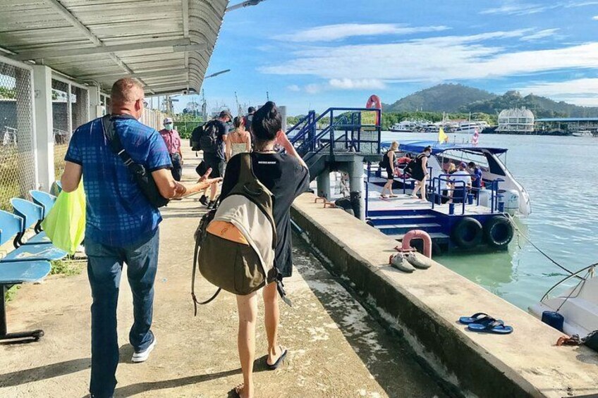 Personas subiendo a un bote, un muelle y una masa de agua. 2