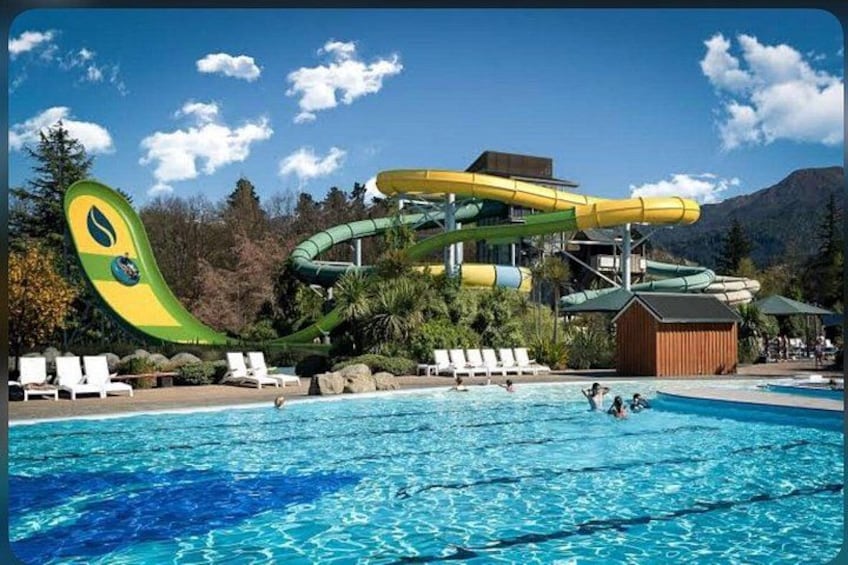 A water park with a large pool, a water slide, and a mountain backdrop. 4
