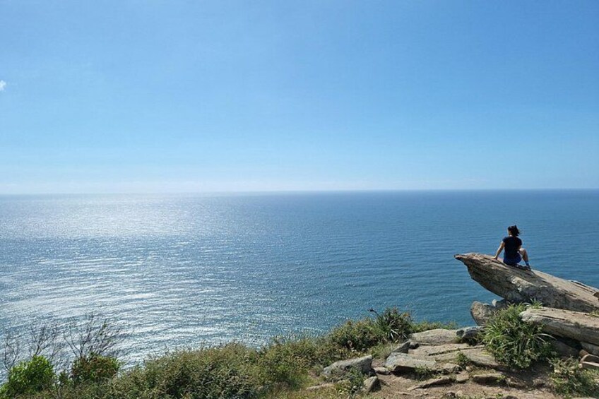 Una persona sentada sobre una roca junto al mar. 3