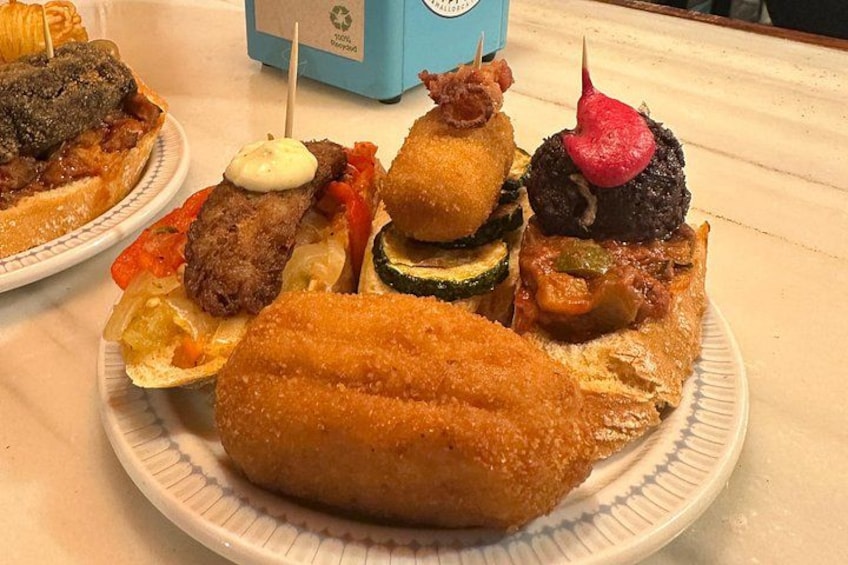 A plate of food with various items including breaded items, vegetables, and a blue container in the background. 5