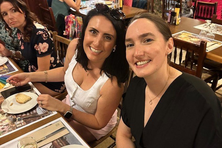 Deux femmes sont assises à une table devant une assiette de nourriture et un verre de vin. 4