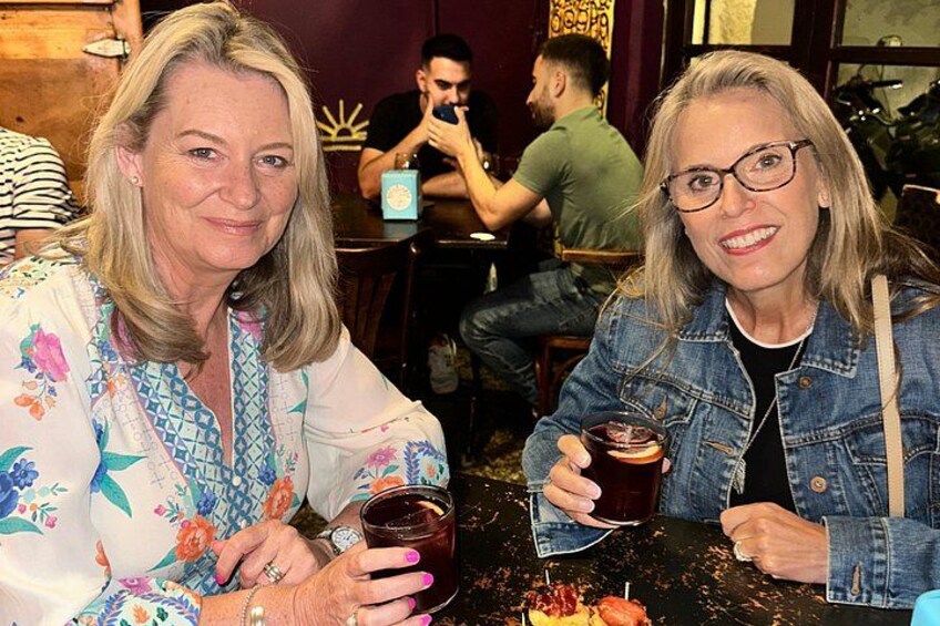 Deux personnes sont assises à une table, devant des boissons, dans un restaurant où d’autres clients sont assis à l’arrière-plan. 2