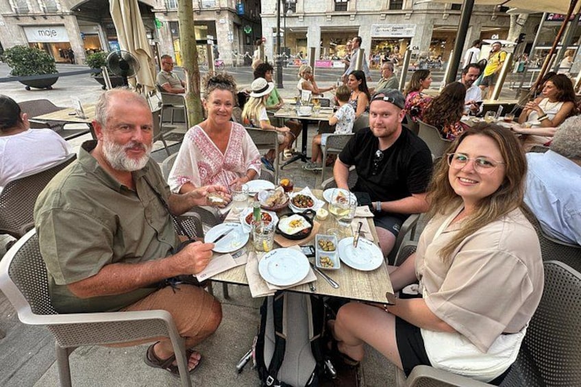 Des personnes sont assises à des tables et des chaises dans un café en plein air. 5