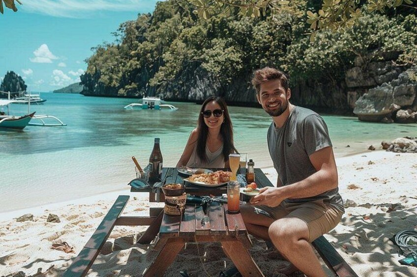 Two people dining at a wooden table on a beach with clear water and boats in the background. 2