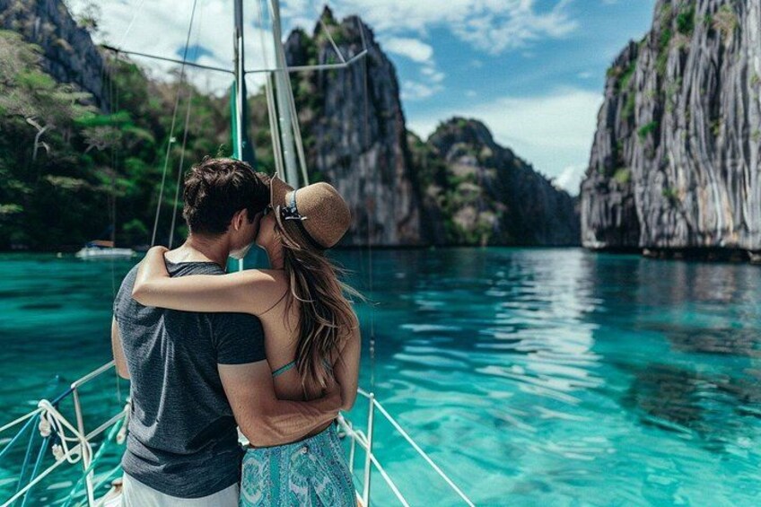 A couple embracing on a boat with clear turquoise water and rocky cliffs in the background. 1