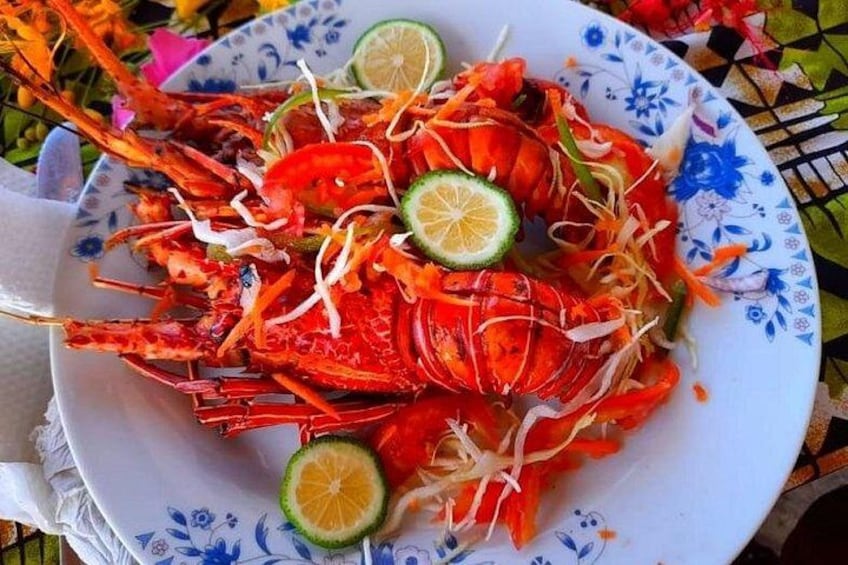 A plate of cooked lobster with lemon slices and shredded vegetables. 2