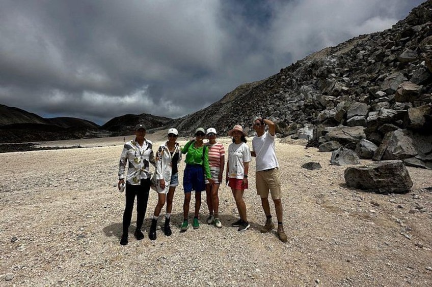 A group of people standing on a rocky beach with mountains in the background. 5